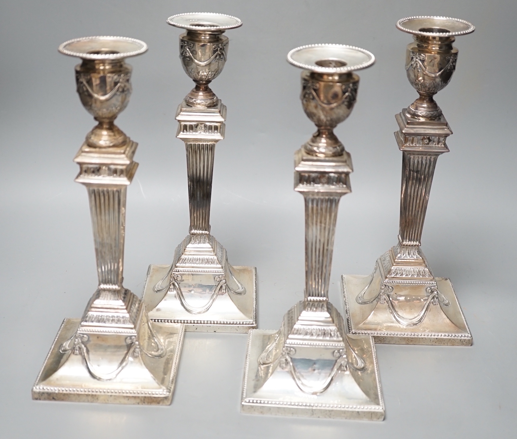 A set of four late Victorian silver candlesticks, with fluted, tapered stems, Hawksworth, Eyre & Co, Sheffield, 1890, 27.5cm, weighted (a.f.).